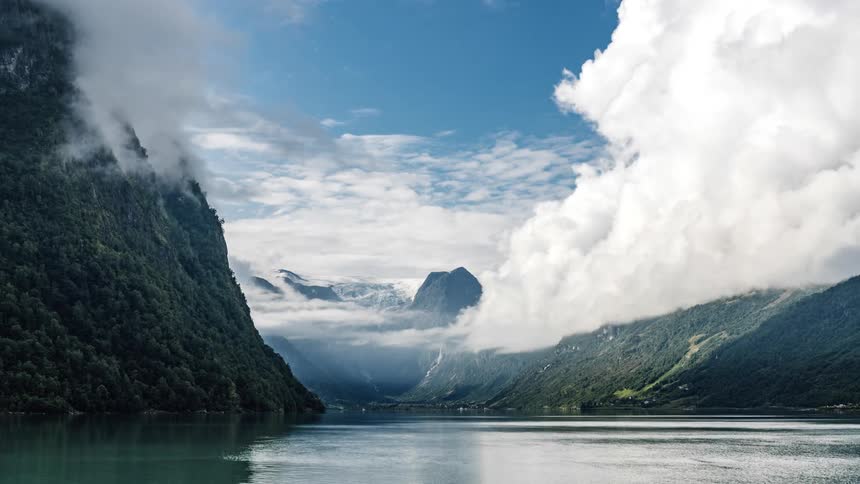 Clouds float above a mountain lake with flowing water