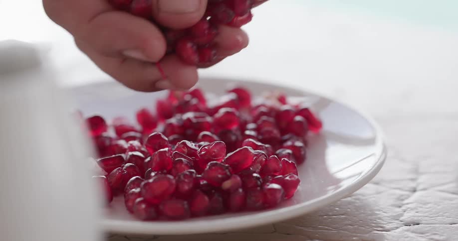 A man picks pomegranate seeds up off of a plate