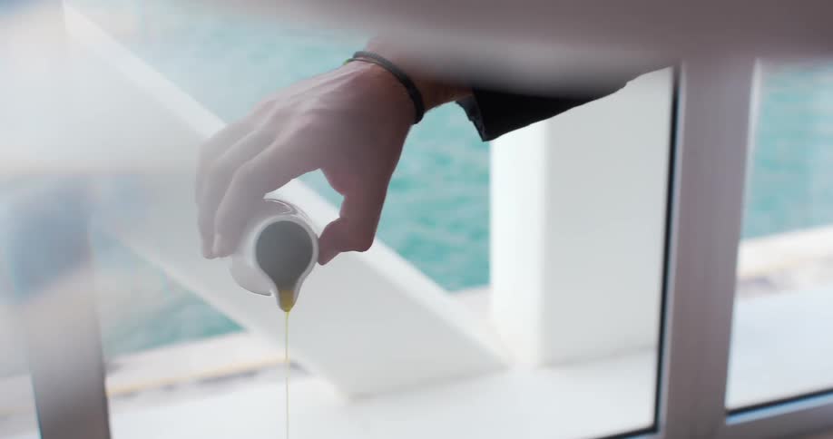A man pours syrup by a window with the water right outside
