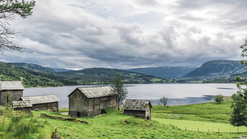 Clouds float over a lake and rural buildings in the summer