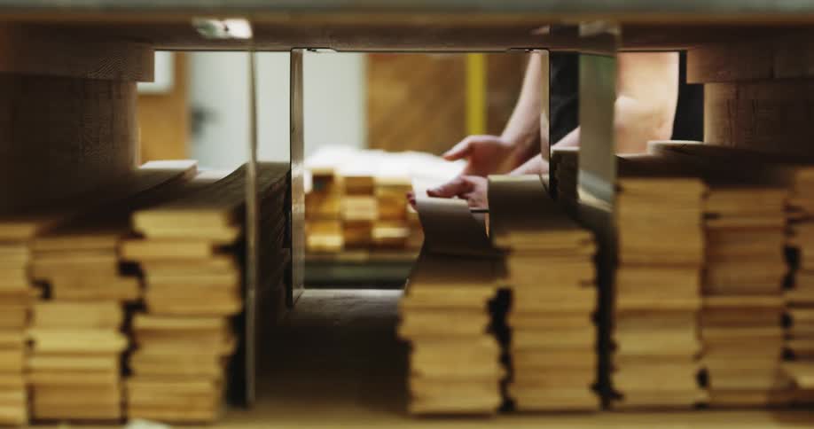 A man stores thin flexible wood planks on a shelf