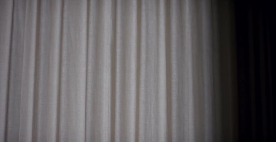 A curtain slowly spreads to cover a window