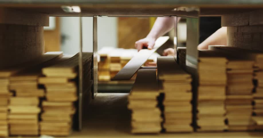A man in a factory picks up a piece of wood