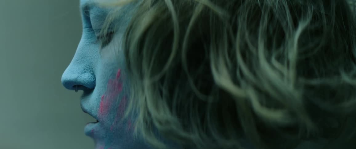 A teen wipes pink makeup on her face and turns her head as she performs