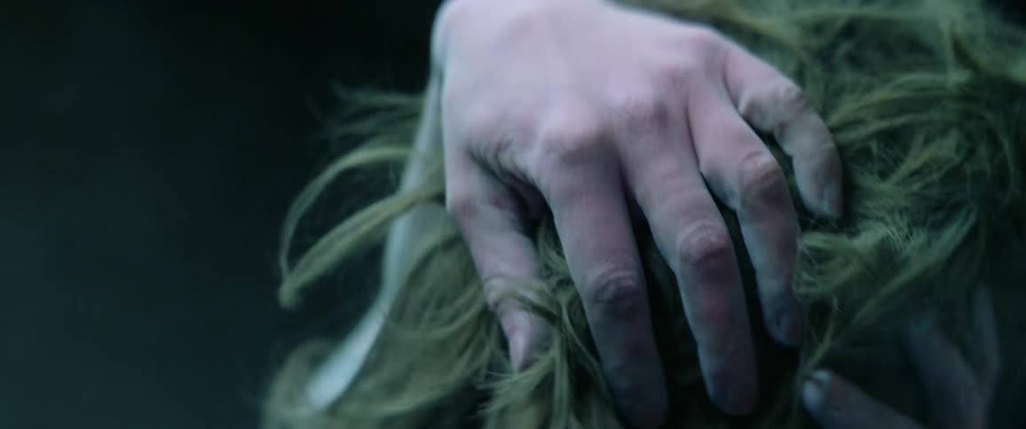 A person with body paint on their skin is running their hands through their hair