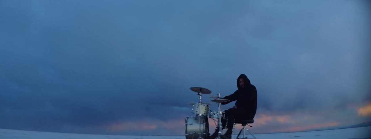 A man on the snow covered landscape plays the drums