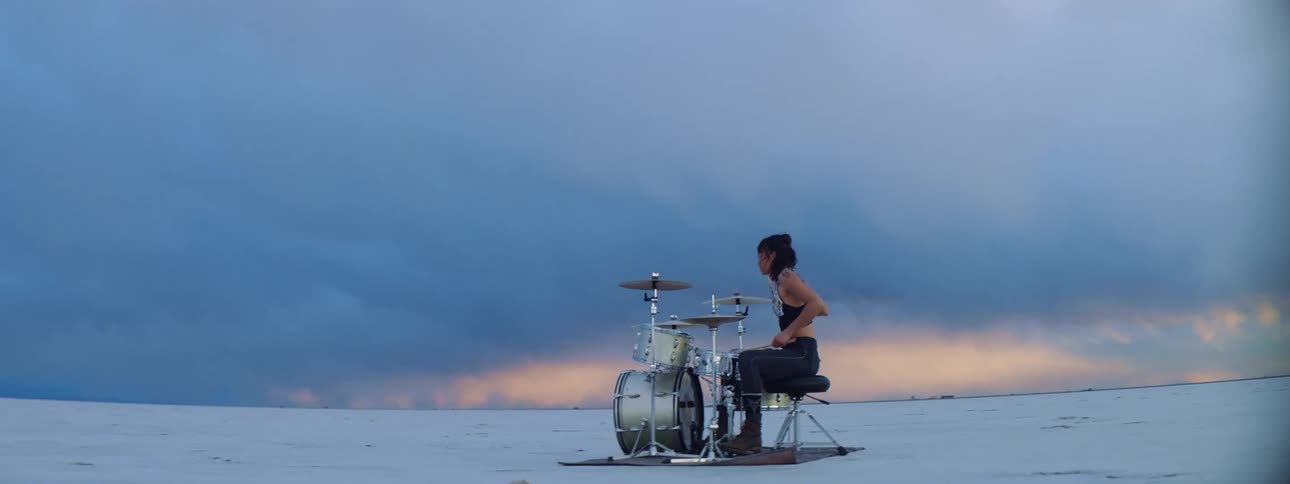 A teenage girl plays drums on a snow covered field