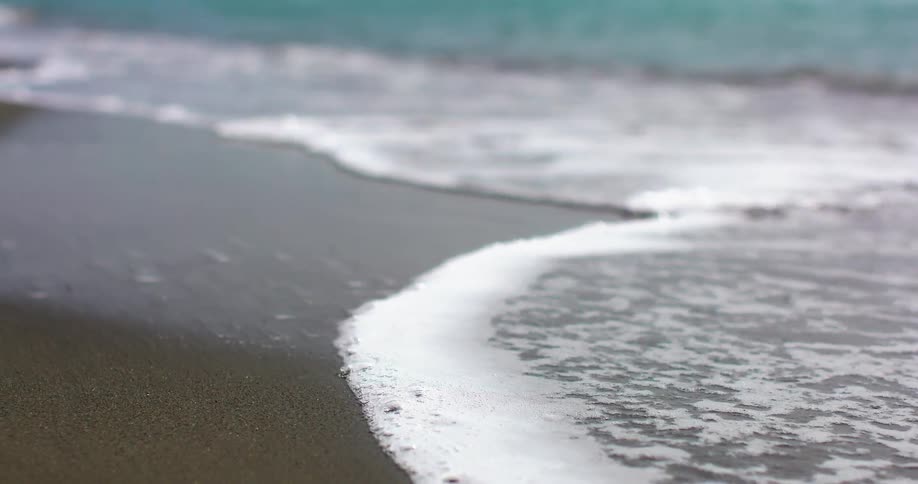 The foamy tide washes onto a beach on a sunny day