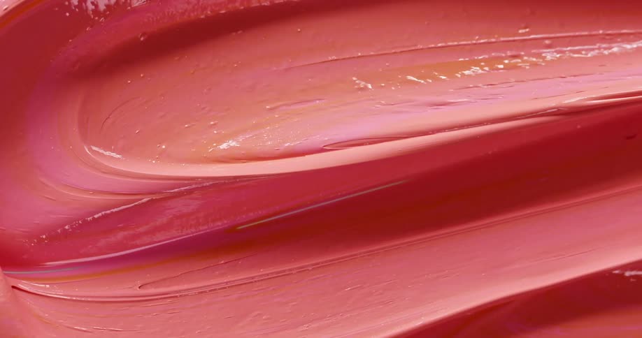 An artist mixes pink and orange paint with a metal palette knife