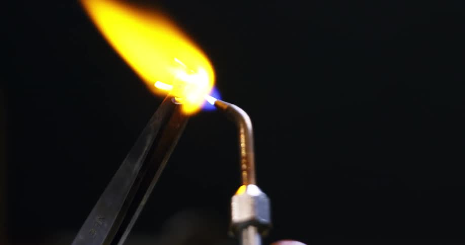 A person is using a torch to heat a piece of metal