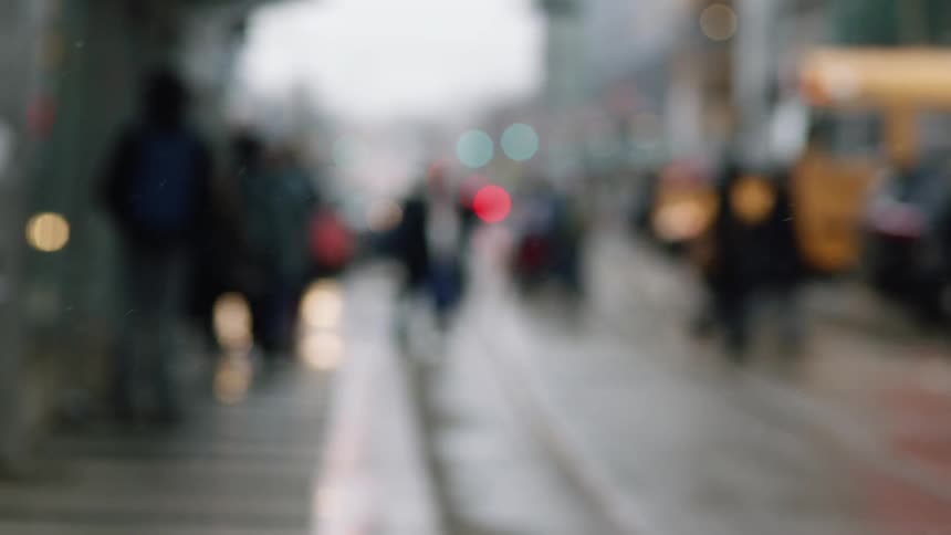 People and vehicles cross a busy city street on a rainy day