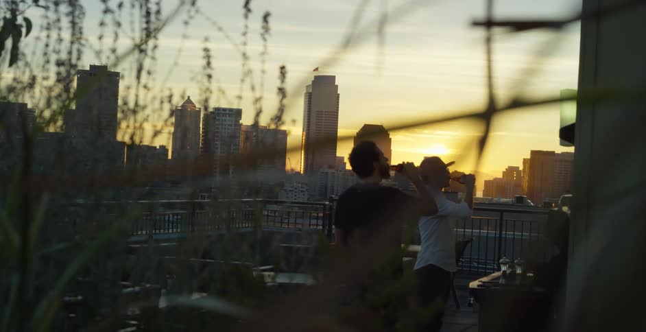 Two men drinking outside near a grill
