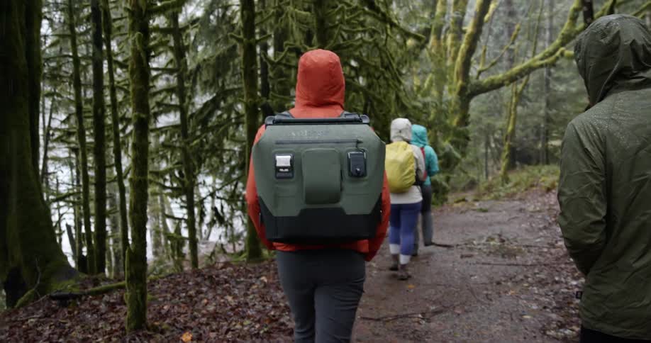 A small group of people hike along a trail through a wooded area