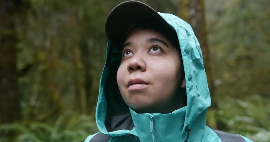 A woman looks around the wet forest