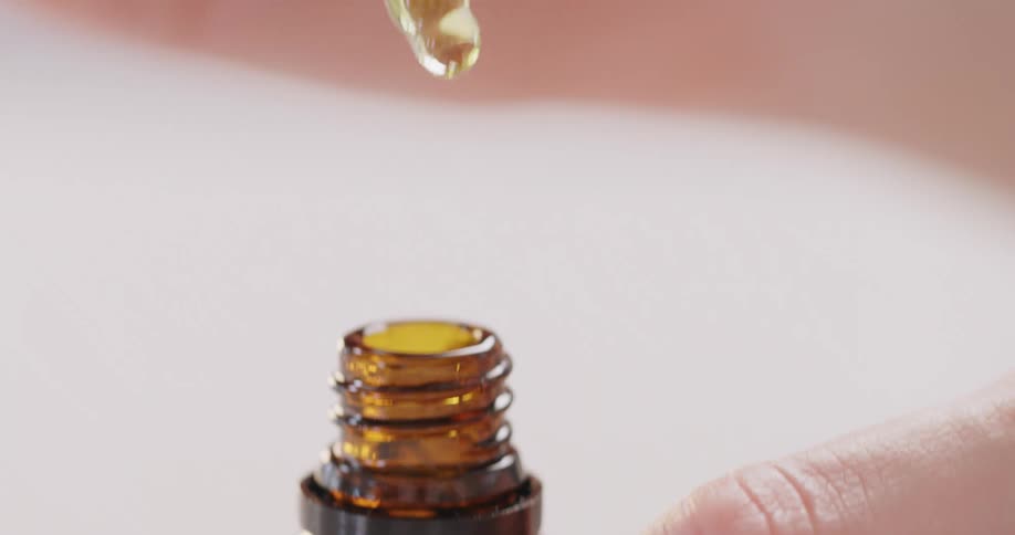 A woman takes a lid off a bottle and pulls the dropper out