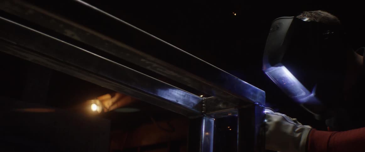A man is welding some metal in a dark area