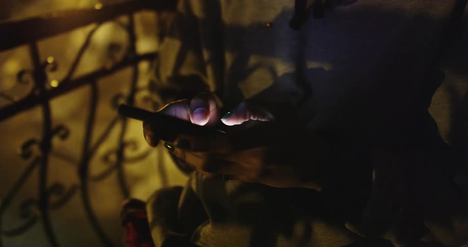 Woman uses a smartphone on the balcony at night