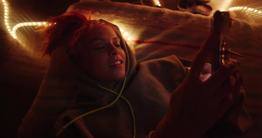 Woman is laying on a couch and using smart phone