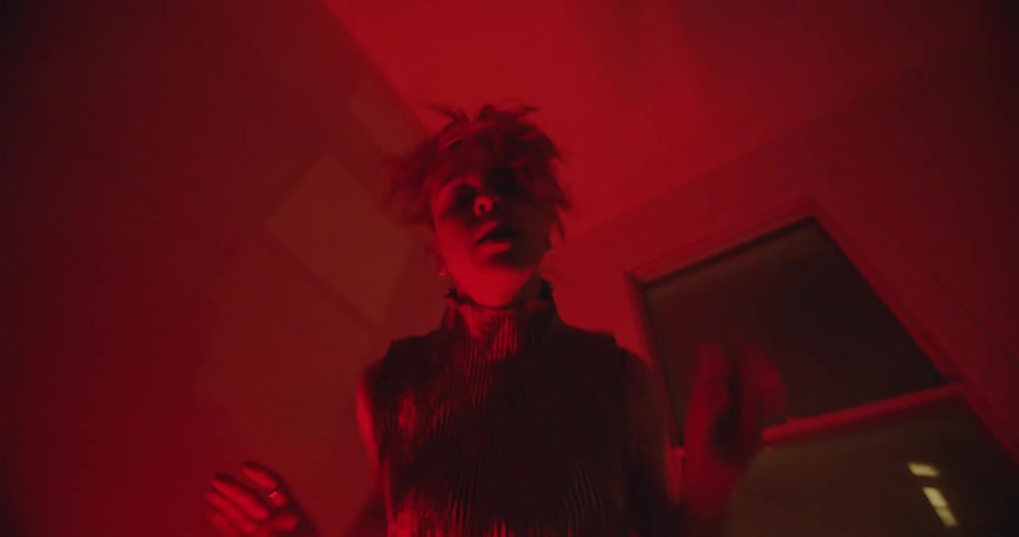 Woman dances wildly in red lit room at night