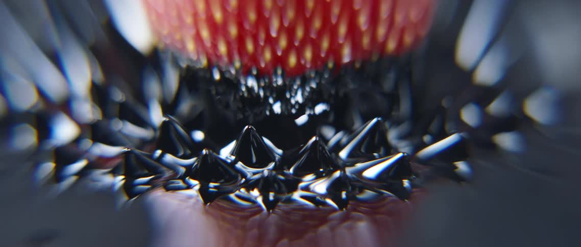 A strawberry is dunked in black liquid
