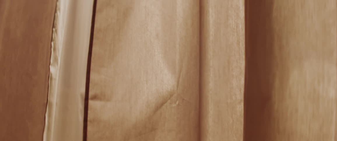 A pair of tan drapes hanging in a window