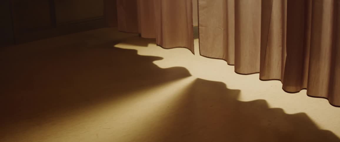Light shines from beneath hanging curtains