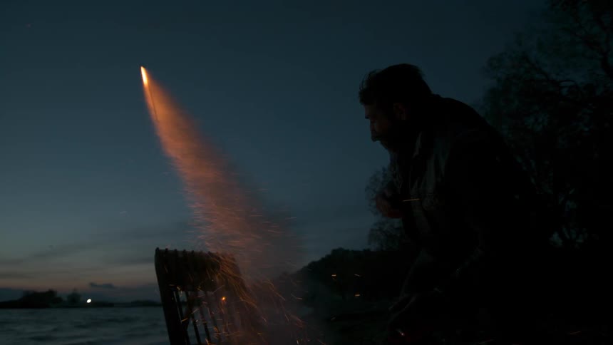 A man lights fireworks from a board at night