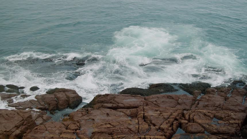 Sea waves crash on the rocky shoreline