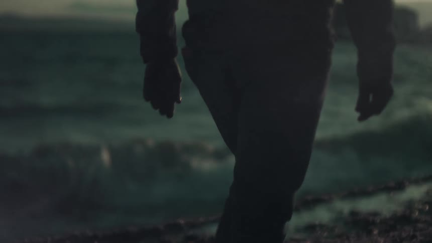 A man walks on the beach at dusk