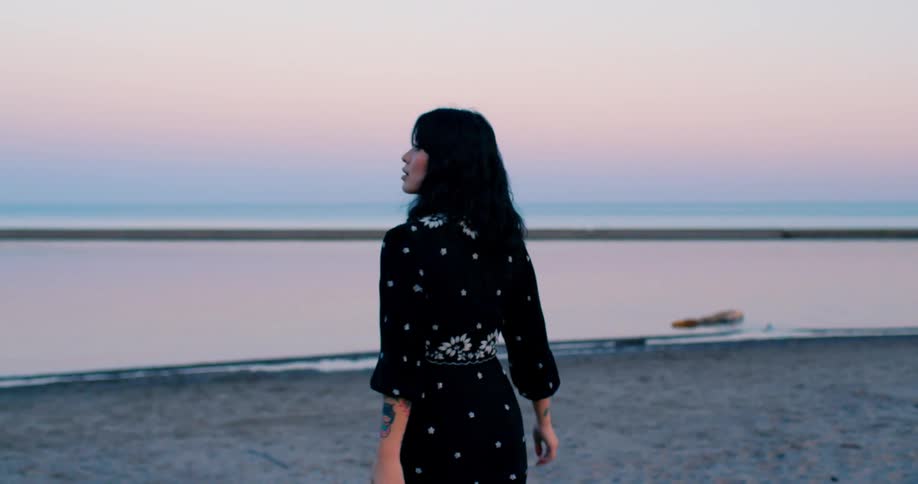 Young asian woman walks on beach at dusk