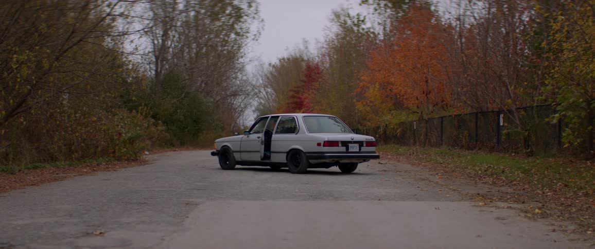 A car sits abandoned on the road in the countryside