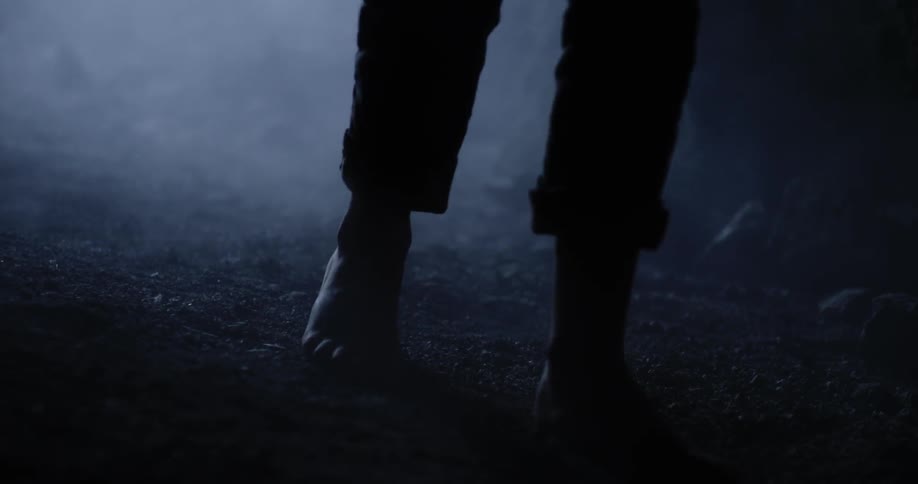 A barefooted child walks in a dark cave