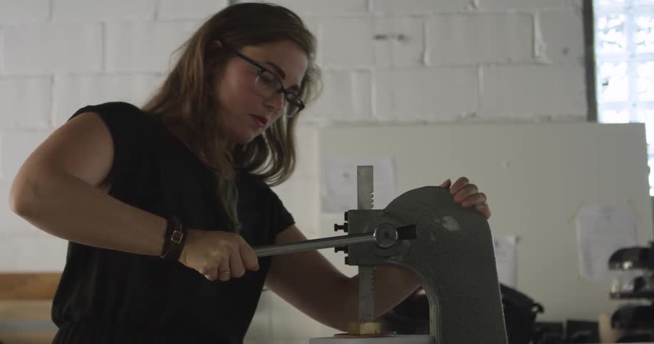 Woman working with a press in a shop area