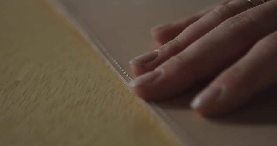 A woman's hand slowly running over the seam in an object