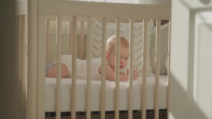 A baby lying in a crib looking around