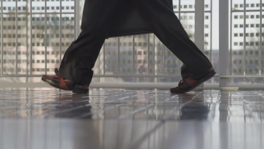 Man wearing a business suit walks inside a terminal at sunset