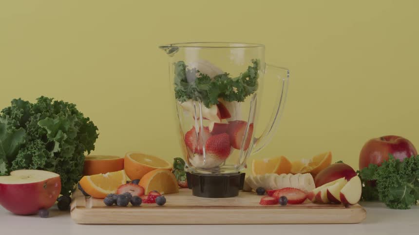 A person fills a blender with fruit and vegetables