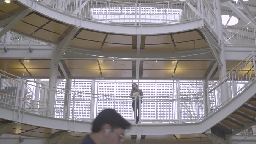 A female standing on a balcony looking forward