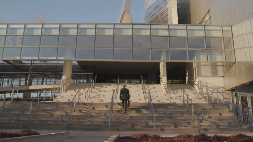 A man is climbing the stairs to the building