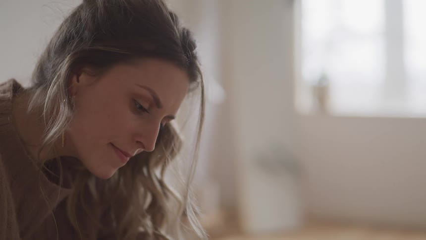 Close up of a blonde womans face sitting in a room meditatively
