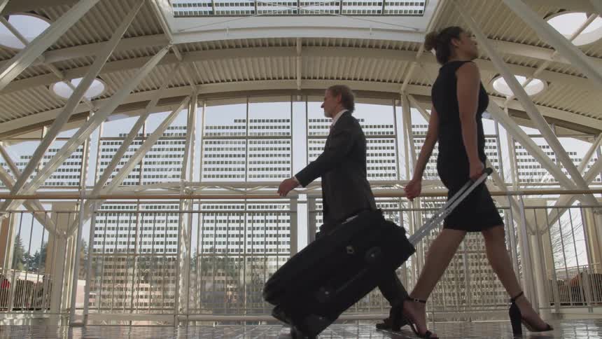 A man and woman walk by one another in an office building