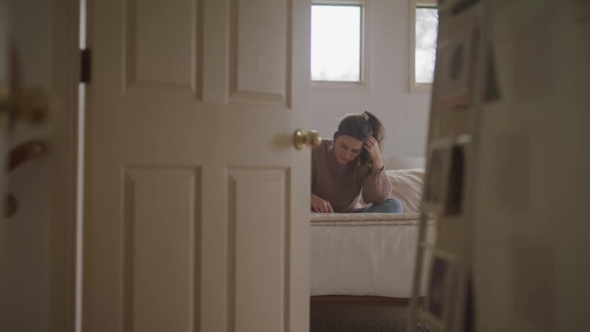 A woman is sitting on a bed indoors