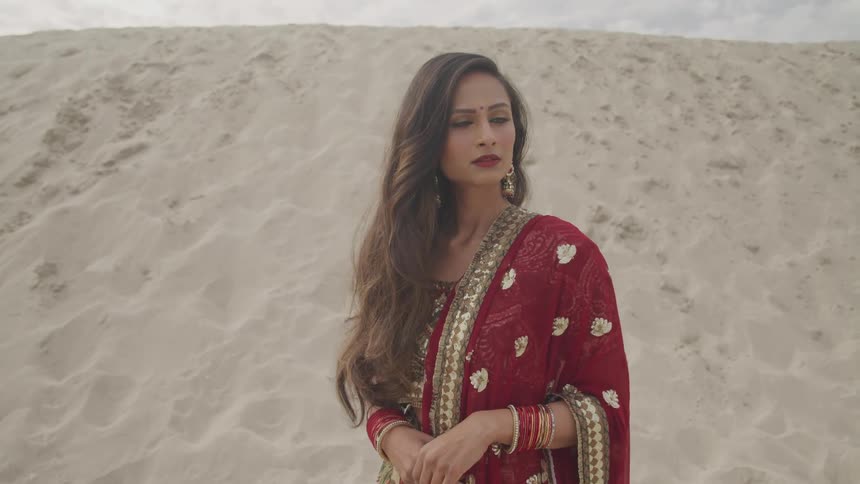 An indian female standing outside in sand