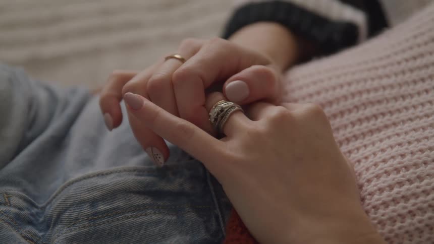 A female lays down while adjusting a bejeweled ring on her left ring finger