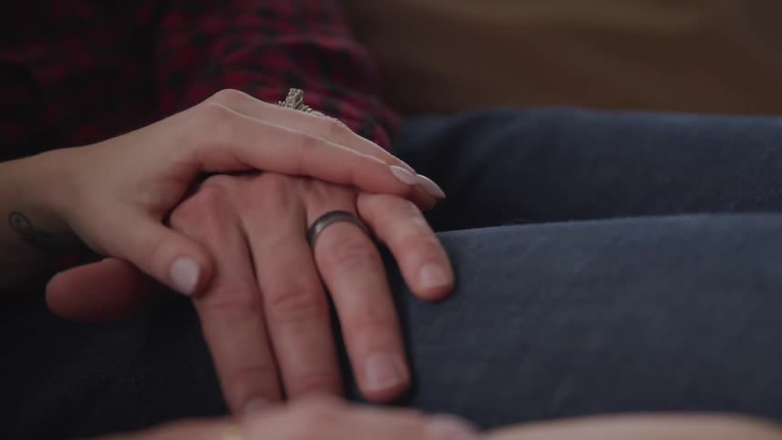 A husband and wife sit and hold hands