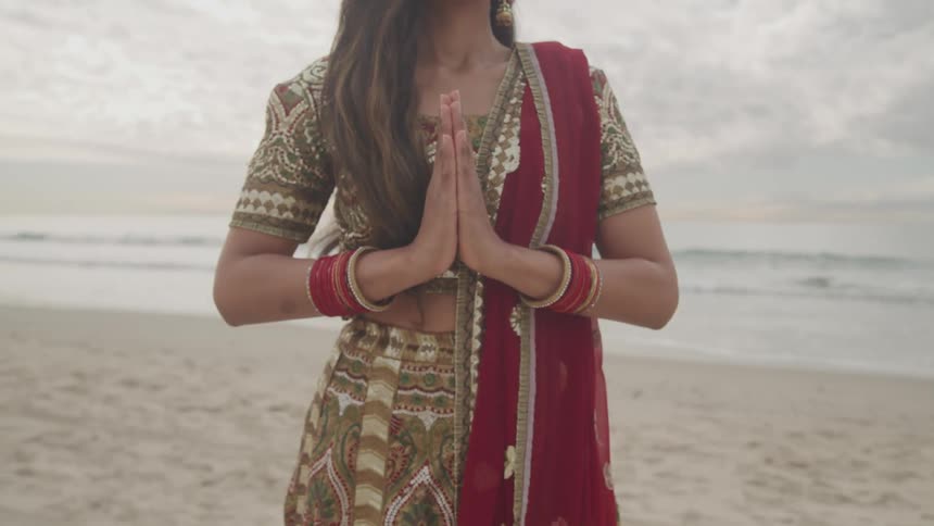 A woman praying on a the beach