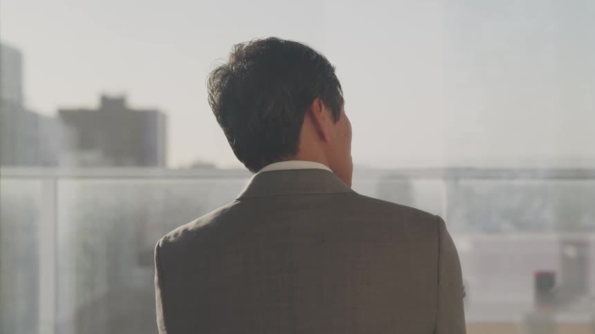Asian businessman looks out the office windows in an office