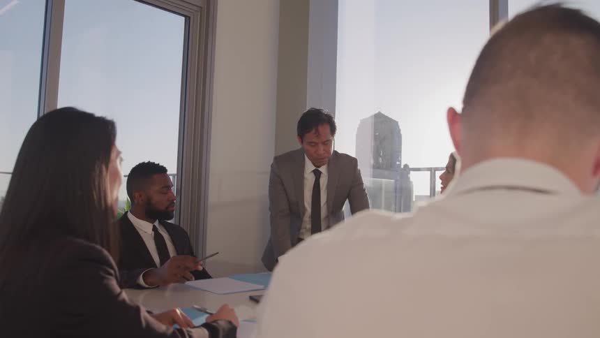Business people sit at a long table conduct a meeting in conference room