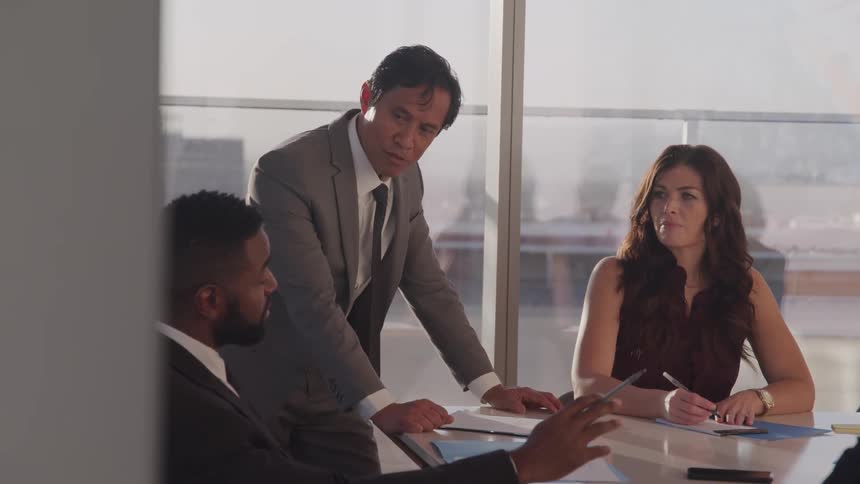 Three employees sit in an office and talk