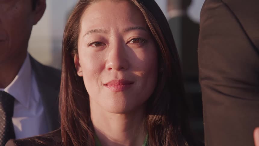 Business woman looks at the camera at sunset